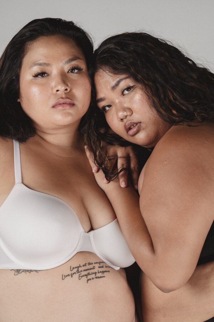 Serious plump Asian women cuddling in studio